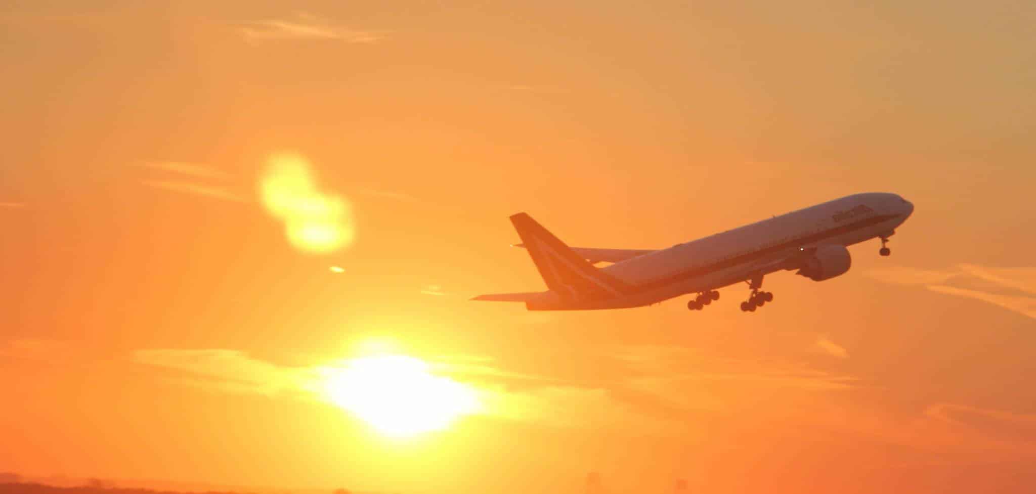 Avion qui décolle devant un couché de soleil